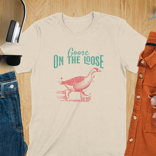 "Goose on the Loose" shirt features a goose on roller skates in motion, with vintage distressed font and colors. Perfect for fans of funny goose shirts, meme tees, sarcastic shirts, silly goose vibes, Y2K clothing, and animal lover gifts.
