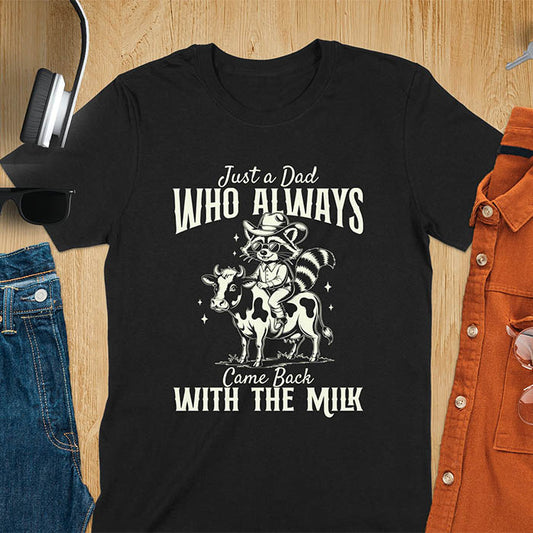 A t-shirt with a raccoon wearing a cowboy hat and sunglasses, riding a cow. Text: Just a Dad WHO ALWAYS above and Came Back WITH THE MILK below. This funny raccoon shirt features funny graphics, a dad t shirt for a funny fathers day or fathers day gift. A funny shirt for dad or gift for dad, a husband gift or father in law gifts. Could be used for a dad announcement, expectant dad, or godfather proposal.