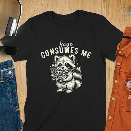 A t-shirt featuring a raccoon holding a bouquet of flowers. Text: Rage CONSUMES ME in a bold, arched font. This dark humor tee is a mental health meme and raccoon meme design. A weirdcore funny and weird funny shirt for a funny gag gift. A raccoon cuteness design, this is one of those shirts that go hard, a unisex and comfortable trendy tee. An animal person gift or girlfriend friend gift, a mom gift alternative.