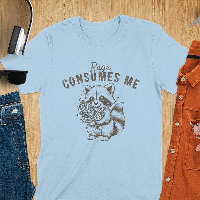 A t-shirt featuring a raccoon holding a bouquet of flowers. Text: Rage CONSUMES ME in a bold, arched font. This dark humor tee is a mental health meme and raccoon meme design. A weirdcore funny and weird funny shirt for a funny gag gift. A raccoon cuteness design, this is one of those shirts that go hard, a unisex and comfortable trendy tee. An animal person gift or girlfriend friend gift, a mom gift alternative.