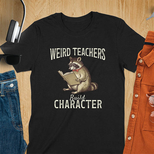 Weird Teachers Build Character shirt featuring a raccoon reading a book with glasses and a red bow tie. Vintage distressed font and brownish monotone give it a retro look. Perfect back-to-school shirt, funny teacher gift, or teacher appreciation tee.