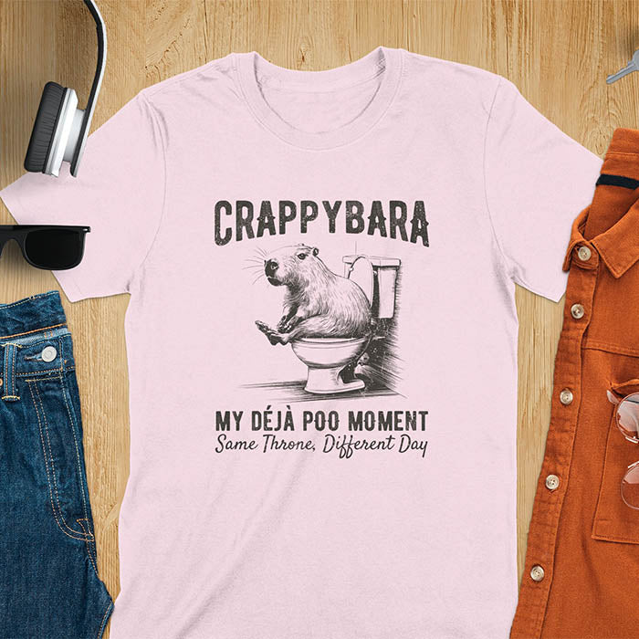 A humorous graphic of a capybara sitting on a toilet with the text Crappybara above and Déjà Poo Moment: same throne, different day below. A funny design for animal and meme lovers.