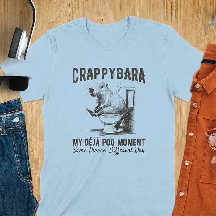 A humorous graphic of a capybara sitting on a toilet with the text Crappybara above and Déjà Poo Moment: same throne, different day below. A funny design for animal and meme lovers.