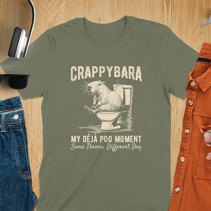 A humorous graphic of a capybara sitting on a toilet with the text Crappybara above and Déjà Poo Moment: same throne, different day below. A funny design for animal and meme lovers.