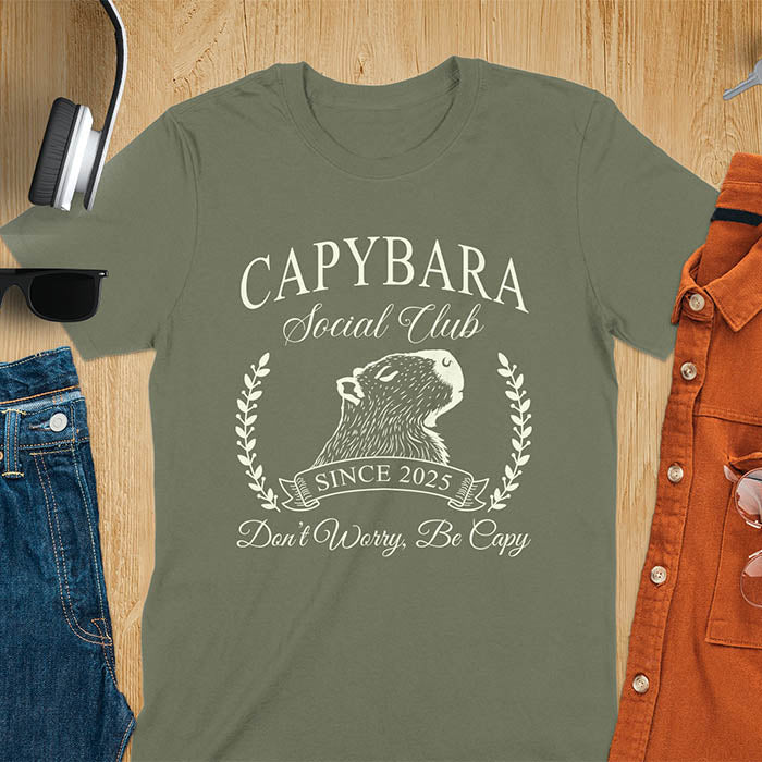 A capybara illustration within a laurel wreath and banner that reads Capybara Social Club Since 2025 and Don't Worry, Be Capy. A retro-inspired design.