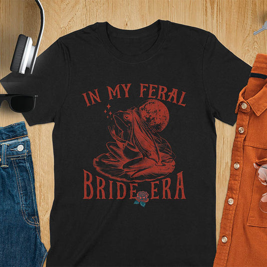 A vintage-style frog wearing a bride veil, croaking to the sky from a lily pad with a moon in the background. Text reads In My Feral Bride Era.