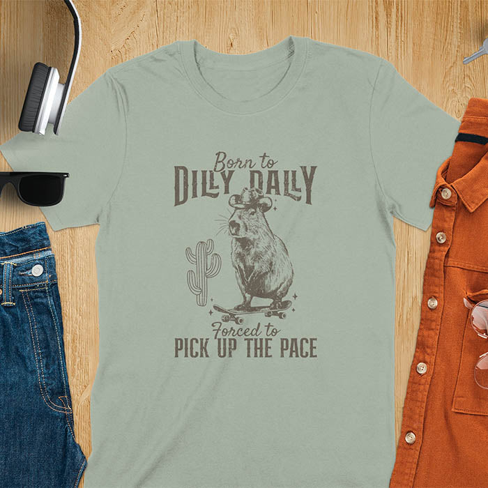 Capybara in a cowboy hat on a skateboard western style. Born to Dilly Dally and Forced to Pick Up the Pace text. Distressed style.