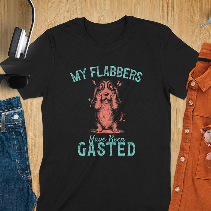 A t-shirt with a startled basset hound puppy. Its characteristic drooping ears are shown, and small lightning bolts radiate from its head. Text: "MY FLABBERS Have Been GASTED". This cute dog tee-shirt displays dog cuteness & cuteness puppy. A funny dog shirt & dog lover gift for dog person, dog mom, dog dad, dog owner. A retro dog shirt & vintage dog tee, animal person gift, gift for mom, hers.