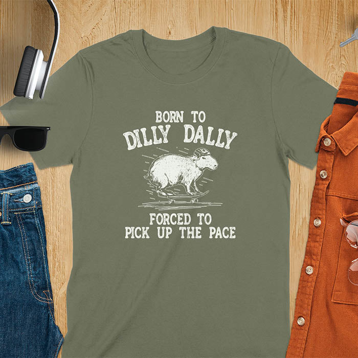A capybara skateboarding, donning a protective helmet .Above it, the words "Born to dilly dally", while below, "Forced to pick up the pace". Rendered in a charming vintage font with a faded look.