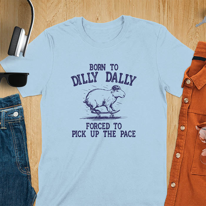A capybara skateboarding, donning a protective helmet .Above it, the words "Born to dilly dally", while below, "Forced to pick up the pace". Rendered in a charming vintage font with a faded look.