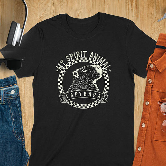 A T-shirt with a graphic of a capybara inside a checkered circle. Above the capybara, text reads "MY SPIRIT ANIMAL," and below, a banner says "CAPYBARA."