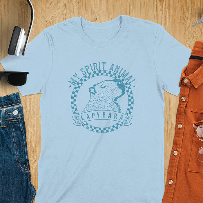 A T-shirt with a graphic of a capybara inside a checkered circle. Above the capybara, text reads "MY SPIRIT ANIMAL," and below, a banner says "CAPYBARA."