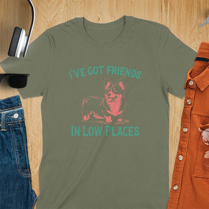 Our vintage-inspired design features a cute corgi silhouette with facial details. Text above it says 'I've Got Friends' and below it says ''In Low Places.' With its retro vibe and distressed texture, this tee adds a touch of nostalgia to your wardrobe.