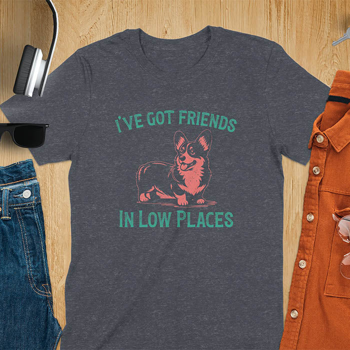 Our vintage-inspired design features a cute corgi silhouette with facial details. Text above it says 'I've Got Friends' and below it says ''In Low Places.' With its retro vibe and distressed texture, this tee adds a touch of nostalgia to your wardrobe.