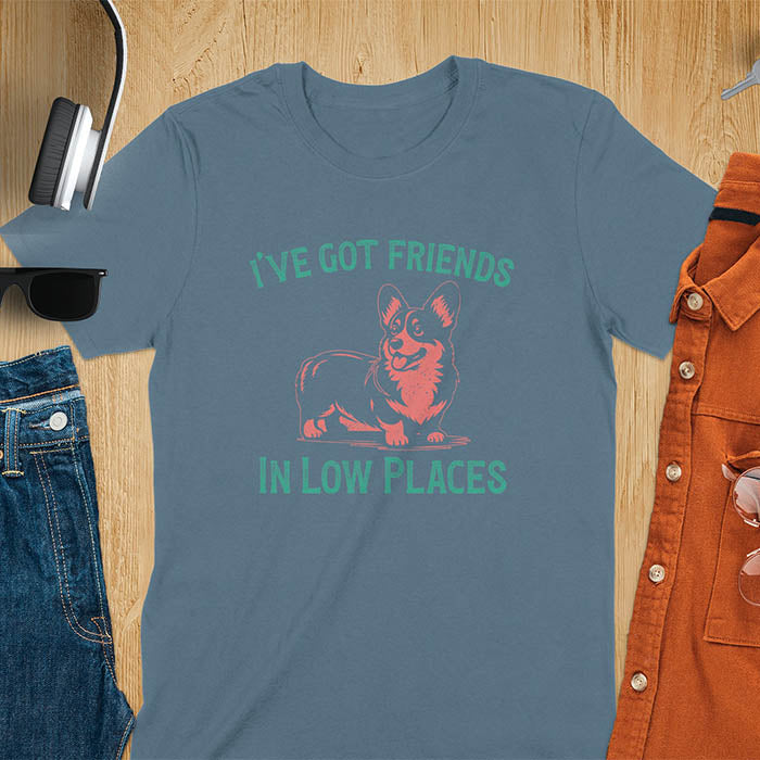 Our vintage-inspired design features a cute corgi silhouette with facial details. Text above it says 'I've Got Friends' and below it says ''In Low Places.' With its retro vibe and distressed texture, this tee adds a touch of nostalgia to your wardrobe.