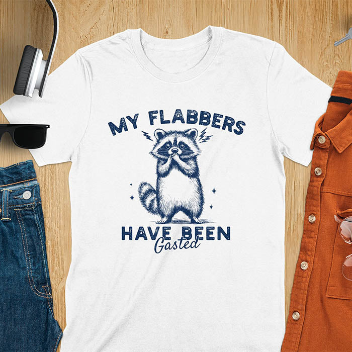 A t-shirt featuring a raccoon with wide eyes and paws covering its mouth. Text: MY FLABBERS above and HAVE BEEN Gasted below in a distressed font. This sarcastic tee-shirt features a funny raccoon with kawaiiness cuteness, a genz meme tee or anxiety tshirt. A depress meme and weirdcore memes design, a funny gag gift for sad core fans. This is one of those shirts that go hard, a trash panda design.