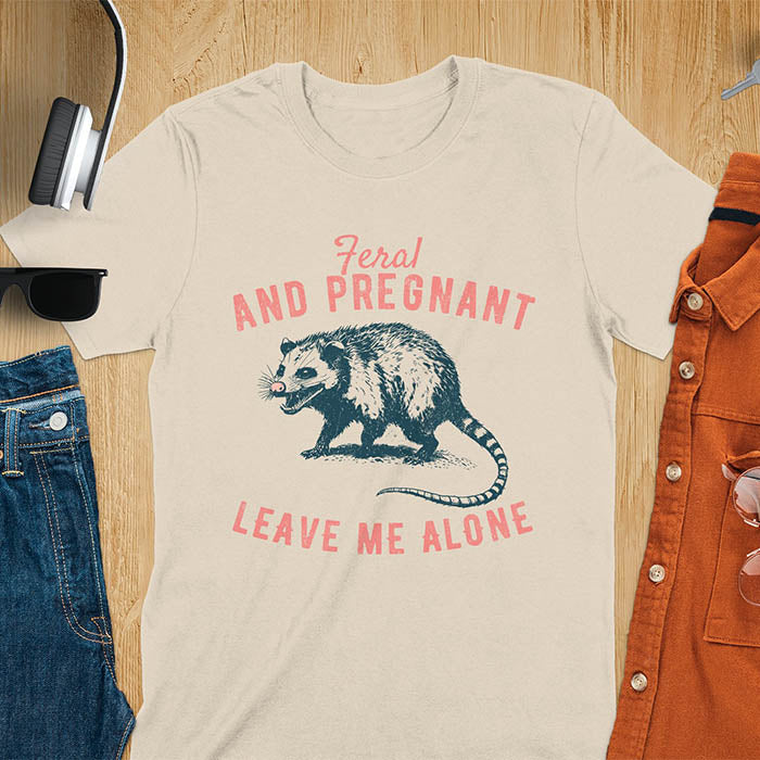 An upset-looking opossum showing its fangs. Text reads Feral and Pregnant and Leave Me Alone.