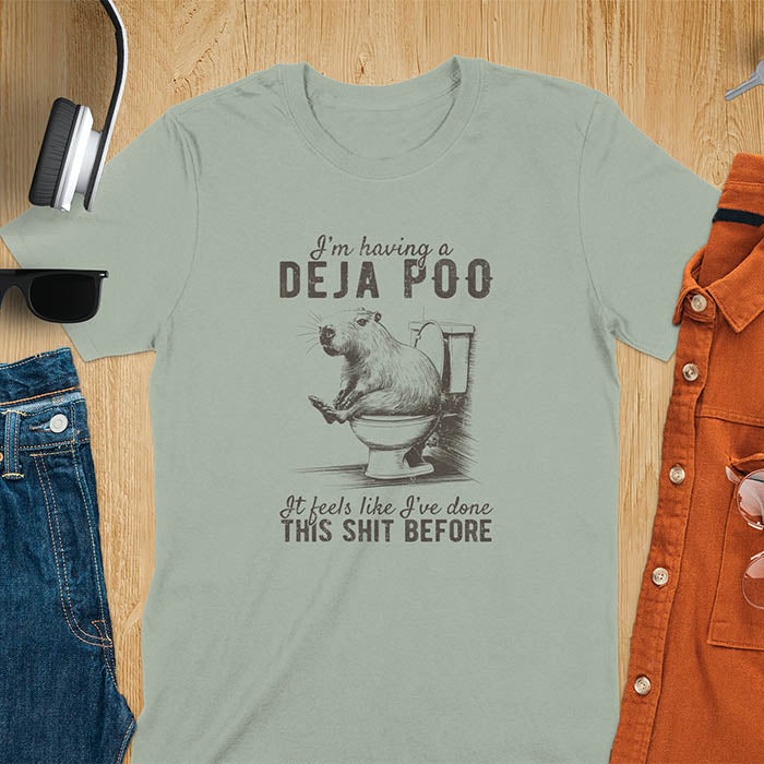 A t-shirt with a capybara seated on a toilet bowl. Text: "I'm having a Deja Poo It feels like I've done THIS SHIT BEFORE". A Capybara Deja Poo Shirt with Toilet Humor Gag Gift appeal. Inappropriate, offensive, weirdcore, funny meme, trending meme, genz gen z tee. Features kawaiiness, capybara cuteness, weird capybara gift. Great for animal person, pet lovers, animal lover, gift mom hers. A Retro Graphic Tshirt, y2k tee-shirt, Vintage Silly Party Tees, shirts that go hard.