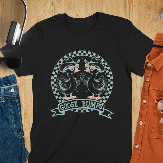 A t-shirt with two geese in cowboy hats and heart sunglasses, within a checkered circle, touching wings. Banner reads "GOOSE BUMPS". This Retro Goose Bump Shirt is a sarcastic goose, silly goose crewneck, Funny Sarcastic Silly Meme Tee. An unhinged tee, weirdcore meme, Snarky Sassy Saying Tee-shirt. A Hilarious Tshirt Gift, gift for goose lover, cowboy cowgirl gift, animal person, gift mom hers, cute animal clothe. Features kawaiiness cuteness.