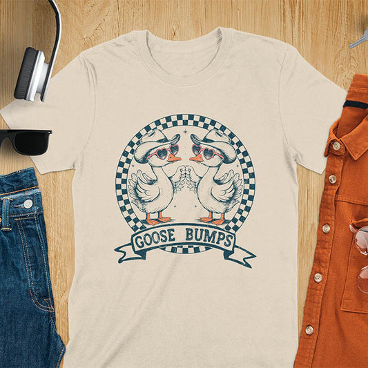 A t-shirt with two geese in cowboy hats and heart sunglasses, within a checkered circle, touching wings. Banner reads "GOOSE BUMPS". This Retro Goose Bump Shirt is a sarcastic goose, silly goose crewneck, Funny Sarcastic Silly Meme Tee. An unhinged tee, weirdcore meme, Snarky Sassy Saying Tee-shirt. A Hilarious Tshirt Gift, gift for goose lover, cowboy cowgirl gift, animal person, gift mom hers, cute animal clothe. Features kawaiiness cuteness.