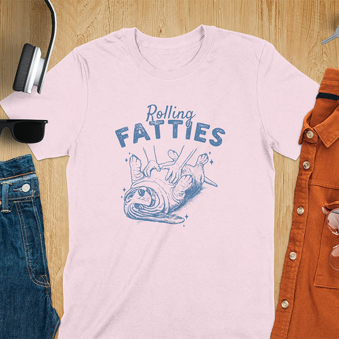 A t-shirt with a basset hound dog on its back getting a belly rub. Text: "Rolling FATTIES". This Rolling Fatties Dog Shirt is a Basset Hound Owner T-shirt, basset hound tee. A Funny Graphic Tee for Dog cuteness gift, Doggy doggie gift, Kawaii Cute Fat Puppy. Perfect gift for dog lover, Dog dad shirt, Dog mama shirt, Dog owner tshirt, pet vintage shirt, Pet lover apparel, Animal Lover Gift, Dog person clothe, Gift mom hers. An Unhinged Tee-shirt, Retro dog shirt, Vintage dog tee.