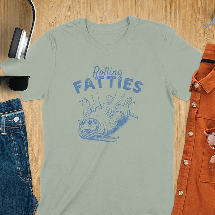 A t-shirt with a basset hound dog on its back getting a belly rub. Text: "Rolling FATTIES". This Rolling Fatties Dog Shirt is a Basset Hound Owner T-shirt, basset hound tee. A Funny Graphic Tee for Dog cuteness gift, Doggy doggie gift, Kawaii Cute Fat Puppy. Perfect gift for dog lover, Dog dad shirt, Dog mama shirt, Dog owner tshirt, pet vintage shirt, Pet lover apparel, Animal Lover Gift, Dog person clothe, Gift mom hers. An Unhinged Tee-shirt, Retro dog shirt, Vintage dog tee.