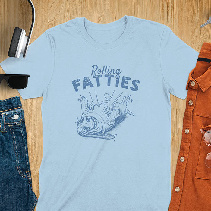 A t-shirt with a basset hound dog on its back getting a belly rub. Text: "Rolling FATTIES". This Rolling Fatties Dog Shirt is a Basset Hound Owner T-shirt, basset hound tee. A Funny Graphic Tee for Dog cuteness gift, Doggy doggie gift, Kawaii Cute Fat Puppy. Perfect gift for dog lover, Dog dad shirt, Dog mama shirt, Dog owner tshirt, pet vintage shirt, Pet lover apparel, Animal Lover Gift, Dog person clothe, Gift mom hers. An Unhinged Tee-shirt, Retro dog shirt, Vintage dog tee.