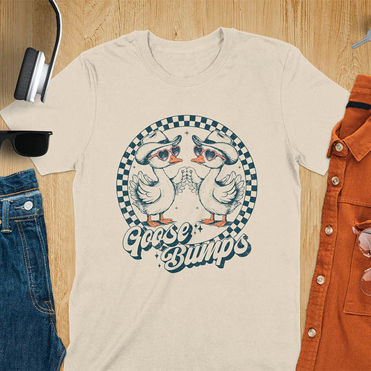 A t-shirt with two geese in cowboy hats and heart sunglasses touching hands, inside a checkered circle. Text "Goose Bumps" is below them on a curved banner. A silly goose crewneck, sarcastic, Funny Sarcastic Meme Tee-shirt, Retro Western Goose Shirt, Snarky Sassy Saying Tshirt, unhinged tee-shirt, weirdcore meme. Ideal gift for goose lover, cowboy cowgirl gift, animal person, gift mom hers. Features kawaiiness cuteness, cute animal clothe, Vintage Silly Humorous Tee Gift.
