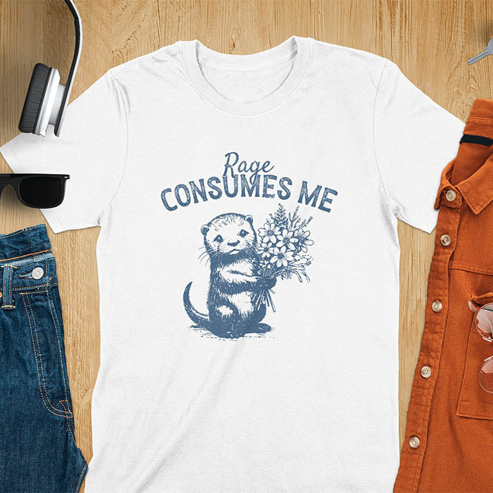A t-shirt with an otter holding flowers. Text: "Rage CONSUMES ME" above. This dark humor tee features otter cuteness and cuteness kawaii, a mental health meme. A genz meme gift and weird funny t shirt, a funny gag gift or animal lover gag. One of those shirts that go hard, an unhinged tshirt. A mom gift hers or animal person gift with a retro graphic tee style.