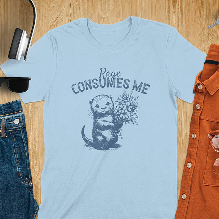 A t-shirt with an otter holding flowers. Text: "Rage CONSUMES ME" above. This dark humor tee features otter cuteness and cuteness kawaii, a mental health meme. A genz meme gift and weird funny t shirt, a funny gag gift or animal lover gag. One of those shirts that go hard, an unhinged tshirt. A mom gift hers or animal person gift with a retro graphic tee style.