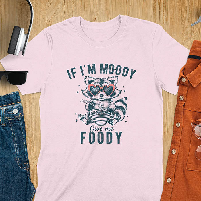 A t-shirt: raccoon in heart sunglasses with noodles. Text: "IF I'M MOODY Give me FOODY". A Funny Raccoon T-shirt, funny trash panda, Vintage Trash Panda Tee. Sarcastic Saying Tee-shirt, snarky humorous, trending funny shirt, meme t shirt, Gag Gift. Features kawaiiness cuteness. Great gift for animal person, Animal Lover Tshirt, mom. Retro aesthetic tee.