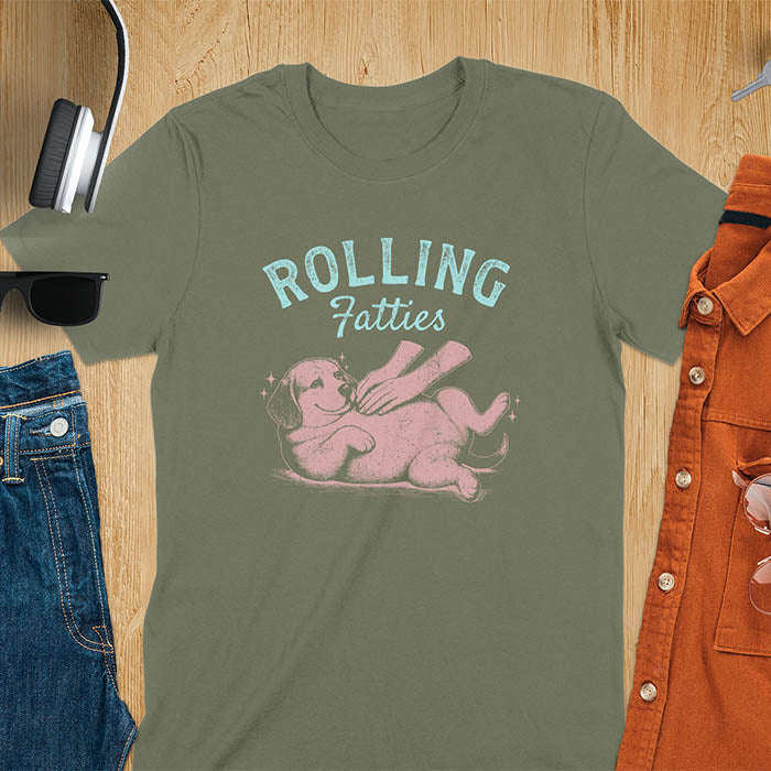 Military green t-shirt featuring 'Rolling Fatties' text in teal lettering above a chubby beagle dog lying on its back in red/burgundy ink sketch style