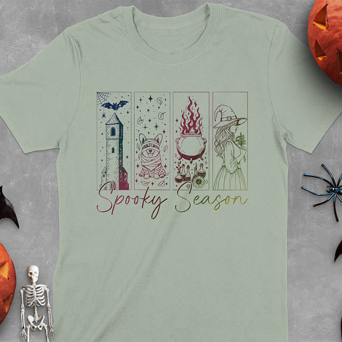 Sage green t-shirt featuring four ombre color panels with haunted house, mummy corgi, bubbling cauldron, and witch figure, with 'Spooky Season' text below