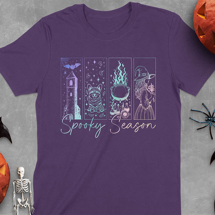 Purple t-shirt featuring four neon panels with haunted house, mummy corgi, bubbling cauldron, and witch figure, with 'Spooky Season' text below