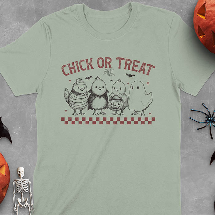 Sage green t-shirt with Funny Halloween Chick Or Treat text featuring cartoon chickens dressed as spooky characters including ghost, mummy, vampire, and trick-or-treater