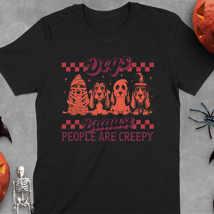 Black t-shirt featuring four basset hounds in Halloween costumes - mummy, ghost, witch, and vampire - with 'Dogs Because People Are Creepy' text and checkered borders