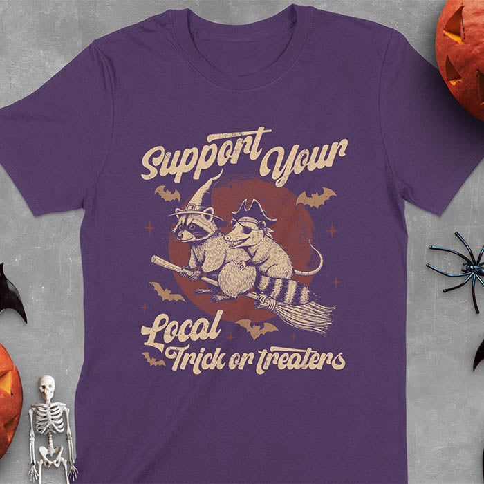 Purple t-shirt Halloween witch raccoon design featuring opossum pirate on broom with Support Your Local Trick or Treaters text