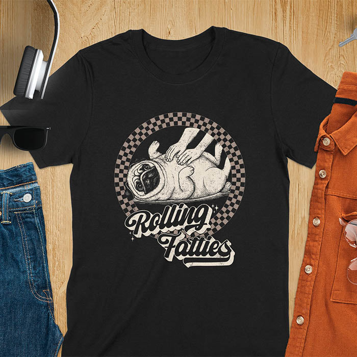Black t-shirt with 'Rolling Fatties' text and illustration of chubby pug lying on its back inside black and white checkered circle border, with human hands reaching toward pug's belly