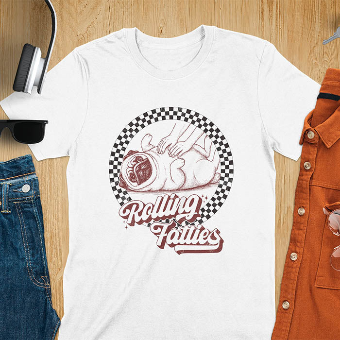 White t-shirt with 'Rolling Fatties' text and illustration of chubby pug lying on its back inside black and white checkered circle border, with human hands reaching toward pug's belly