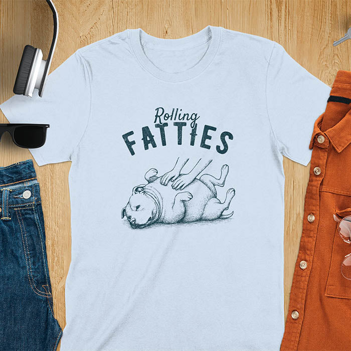 Light blue t-shirt with 'Rolling Fatties' text and illustration of chubby pitbull dog lying on its back with paws up, with human hands on the dog's belly