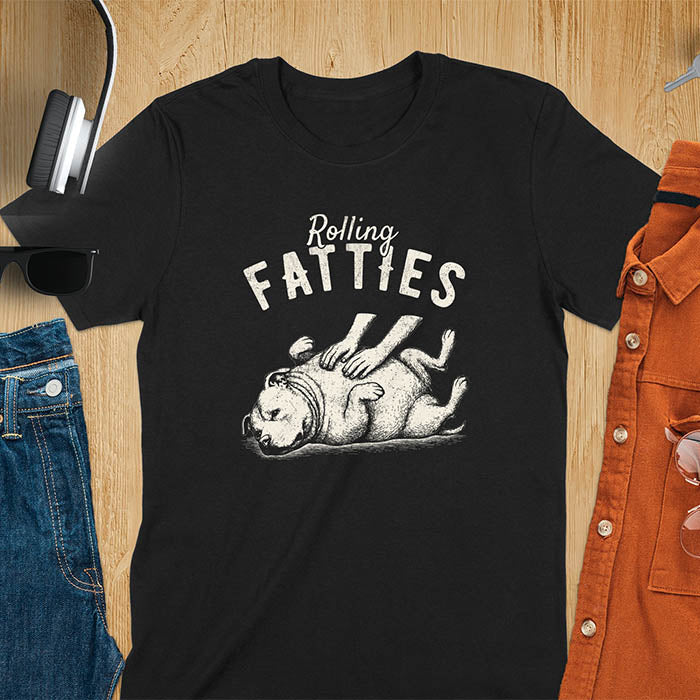 Black t-shirt with 'Rolling Fatties' text and illustration of chubby pitbull dog lying on its back with paws up, with human hands on the dog's belly