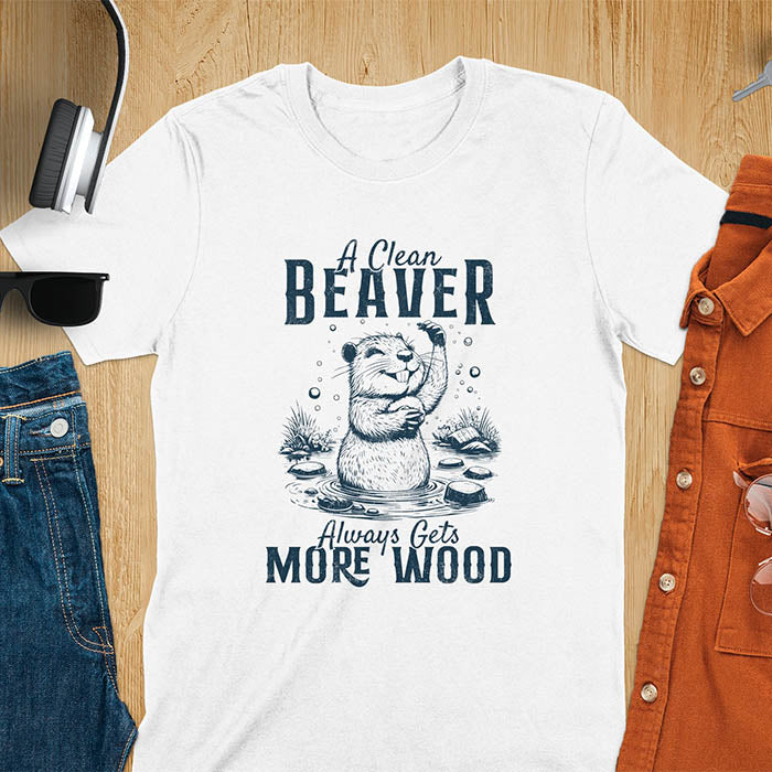 White t-shirt featuring illustrated beaver bathing in water with text 'A Clean Beaver Always Gets More Wood' - adult humor meme design with cartoon beaver surrounded by water bubbles and tree stumps