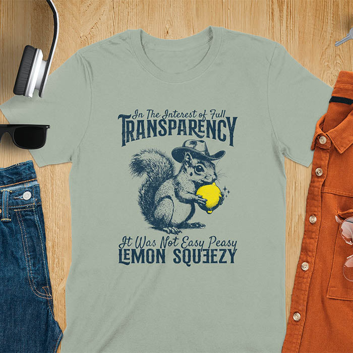 Sage green t-shirt featuring illustrated squirrel wearing cowboy hat and holding yellow lemon with text 'In The Interest of Full Transparency It Was Not Easy Peasy Lemon Squeezy' - funny sarcastic meme design