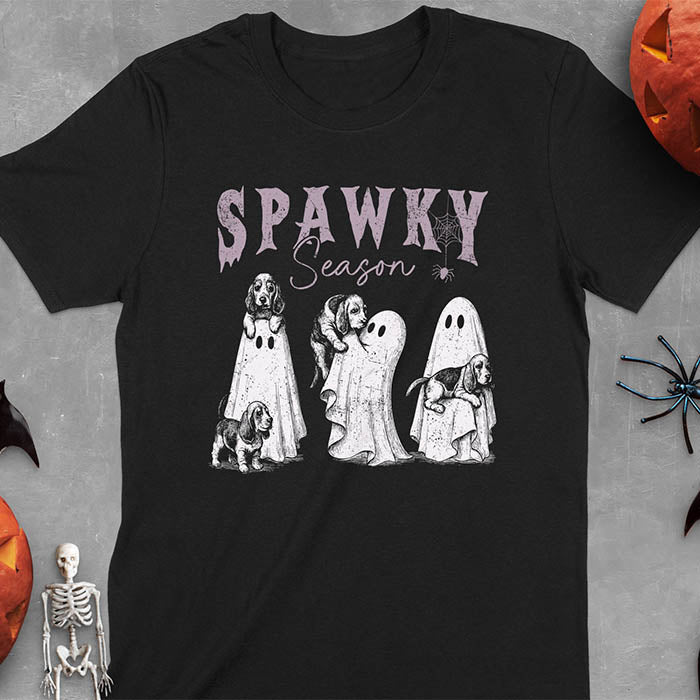 Black Halloween T-shirt featuring 'SPAWKY Season' text with cute white ghosts carrying Basset Hound puppies, designed in purple ink with playful Halloween theme