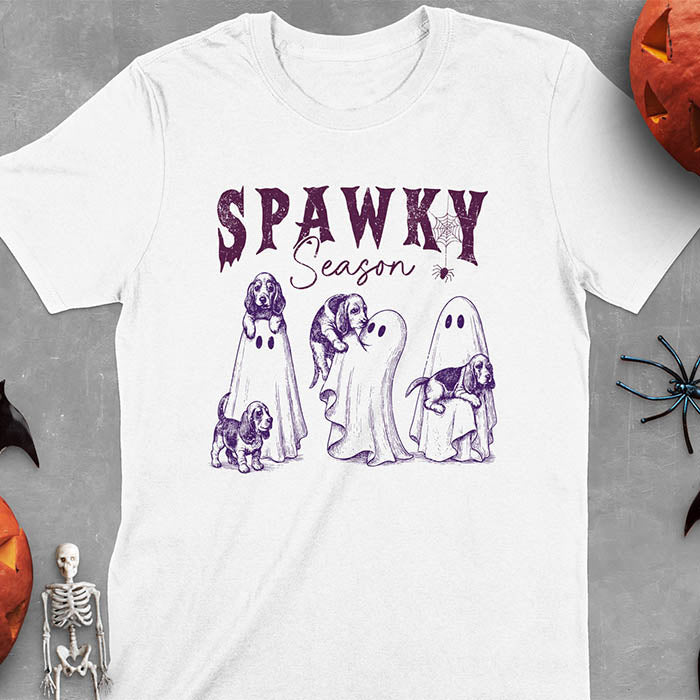 White Halloween T-shirt featuring 'SPAWKY Season' text with cute ghosts carrying Basset Hound puppies, designed in purple ink with playful Halloween theme