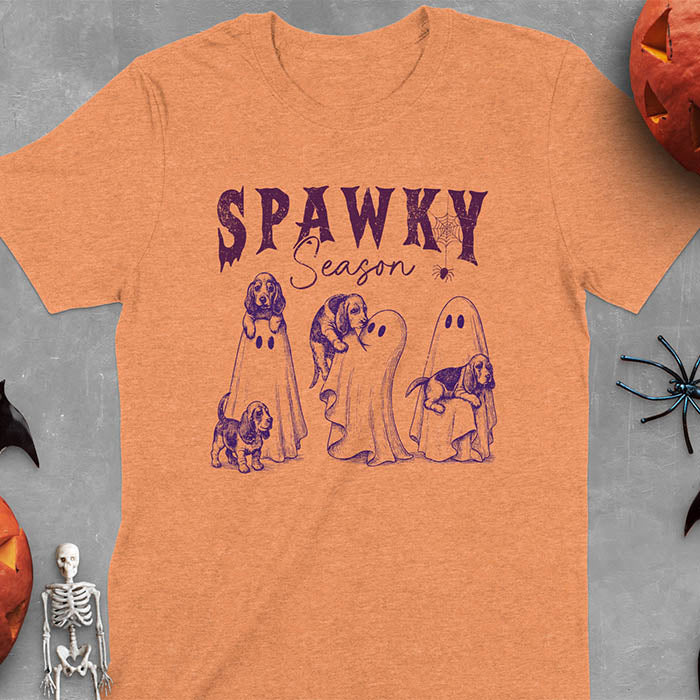Heather Orange Halloween T-shirt featuring 'SPAWKY Season' text with cute white ghosts carrying Basset Hound puppies, designed in purple ink with playful Halloween theme