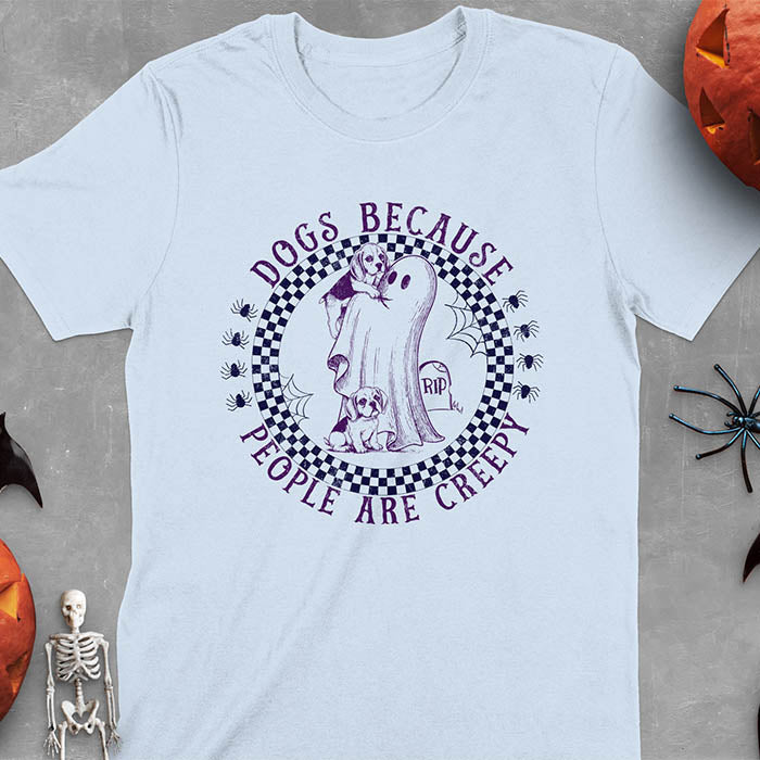 Light blue Halloween t-shirt featuring a cute ghost holding a beagle puppy with another beagle sitting on the ground next to a tombstone marked 'RIP', surrounded by spiders in a circular checkered border design with text 'DOGS BECAUSE PEOPLE ARE CREEPY'