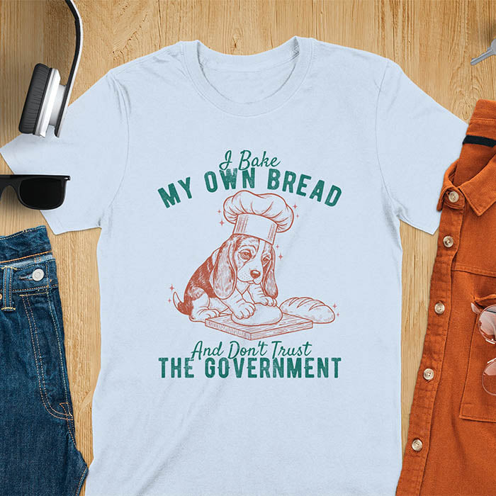 Light blue Basset Hound chef t-shirt with text 'I Bake MY OWN BREAD And Don't Trust THE GOVERNMENT' featuring basset puppy in chef's hat