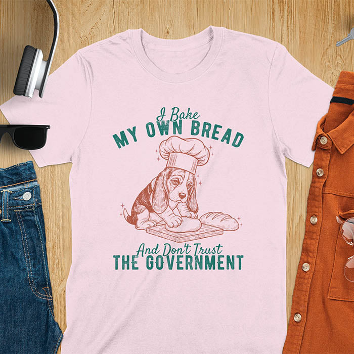 Light Pink Basset Hound chef t-shirt with text 'I Bake MY OWN BREAD And Don't Trust THE GOVERNMENT' featuring basset puppy in chef's hat