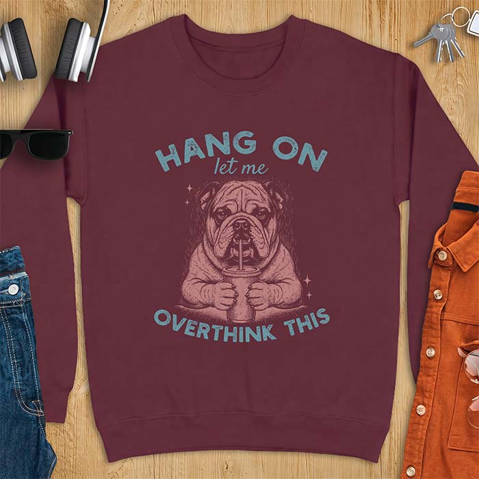 Maroon sweatshirt with a graphic of an English Bulldog holding an iced coffee with a straw, with the text Hang On Let Me Overthink This